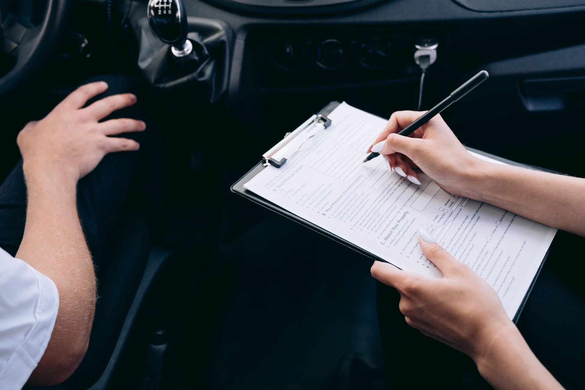 Person filling in a form on a clipboard inside a car
