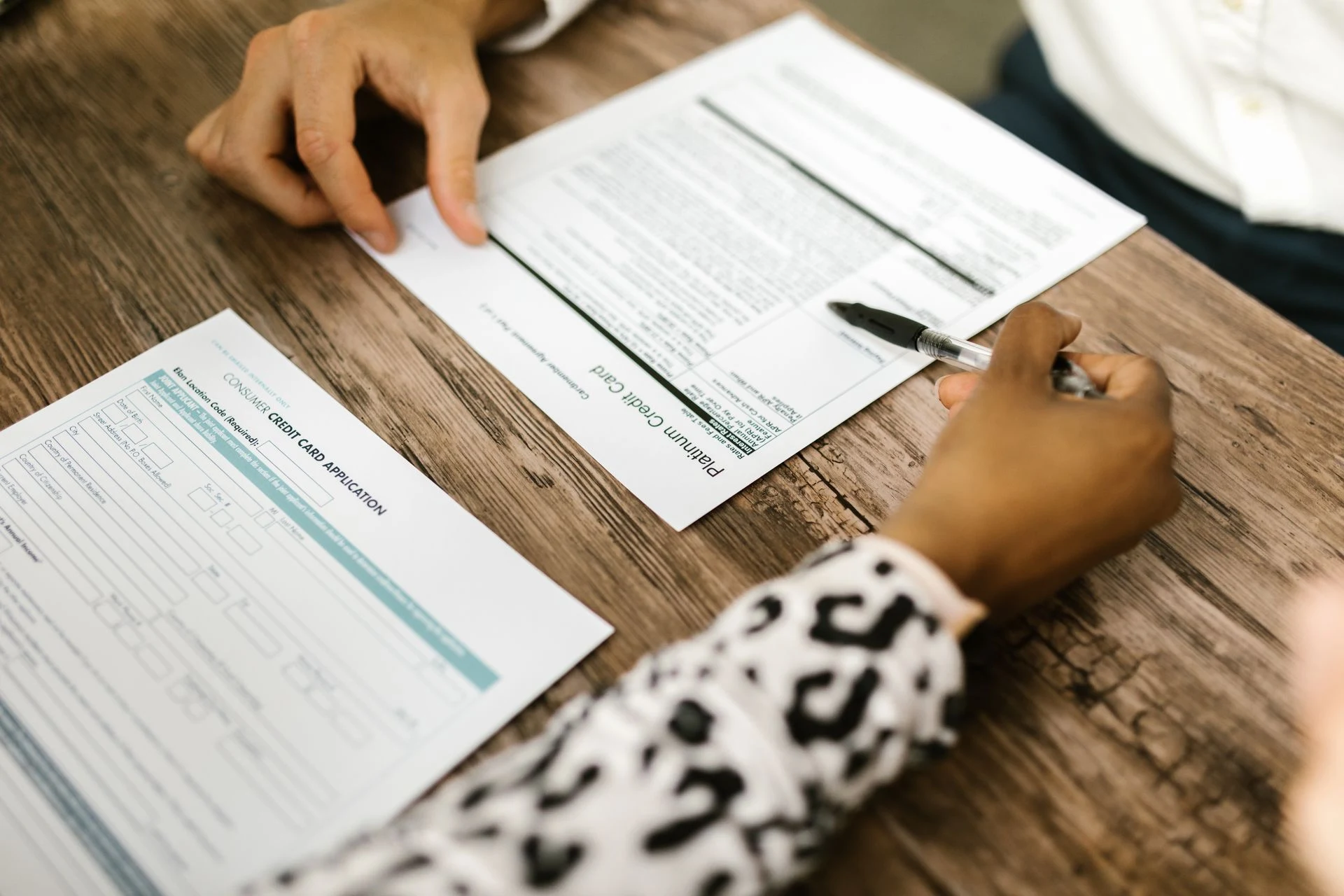 Hand completing a printed application form on a table