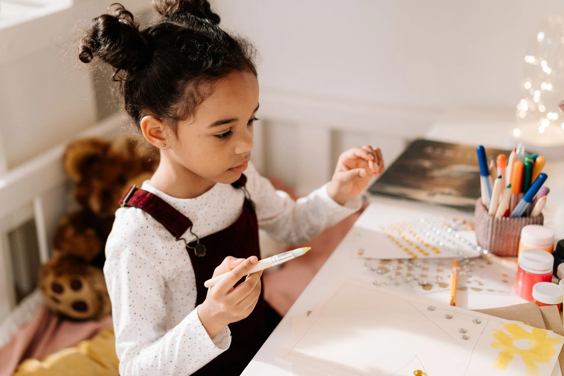 Young girl drawing at a table with coloured pencils