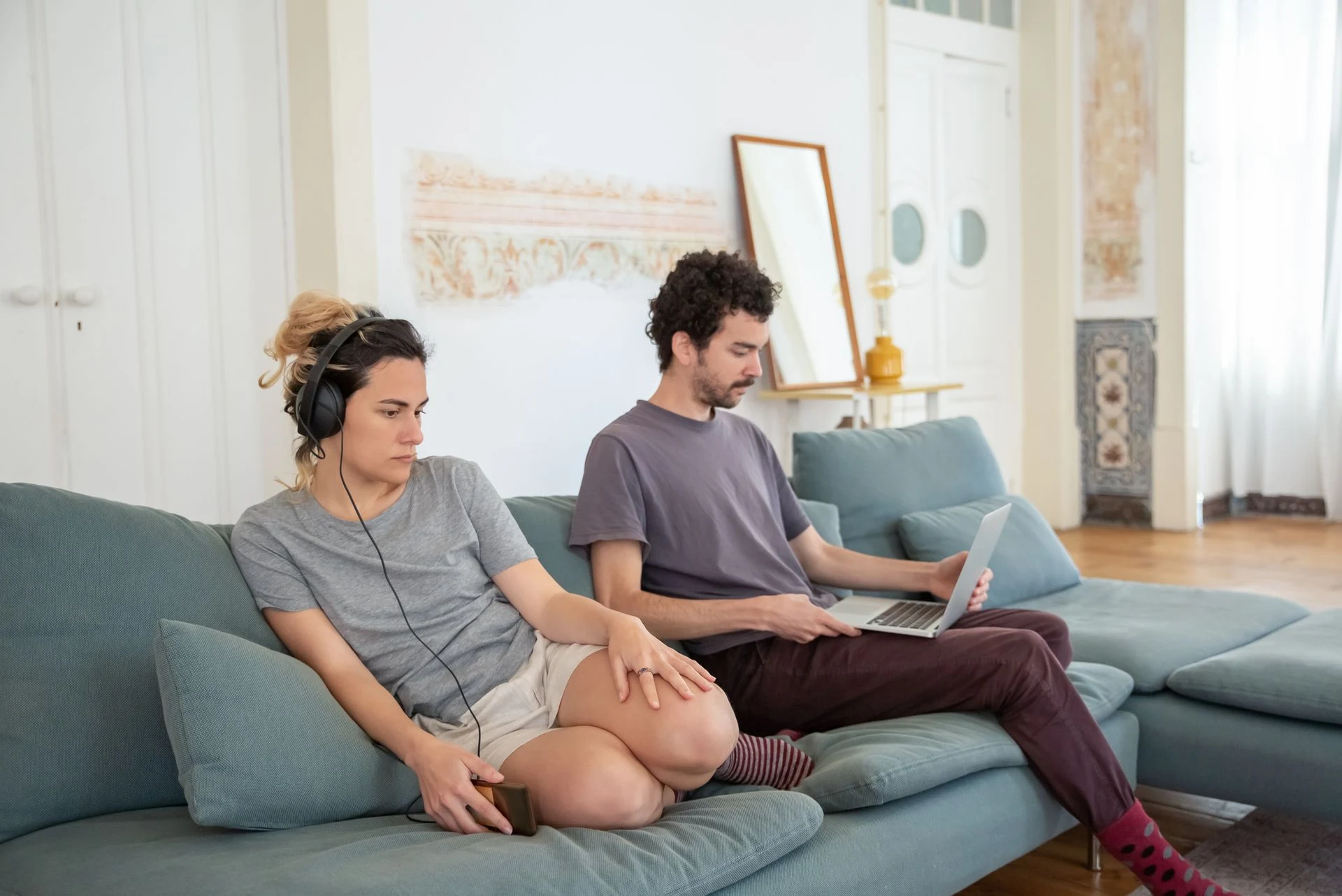 Couple sitting at opposite ends of a sofa, not speaking