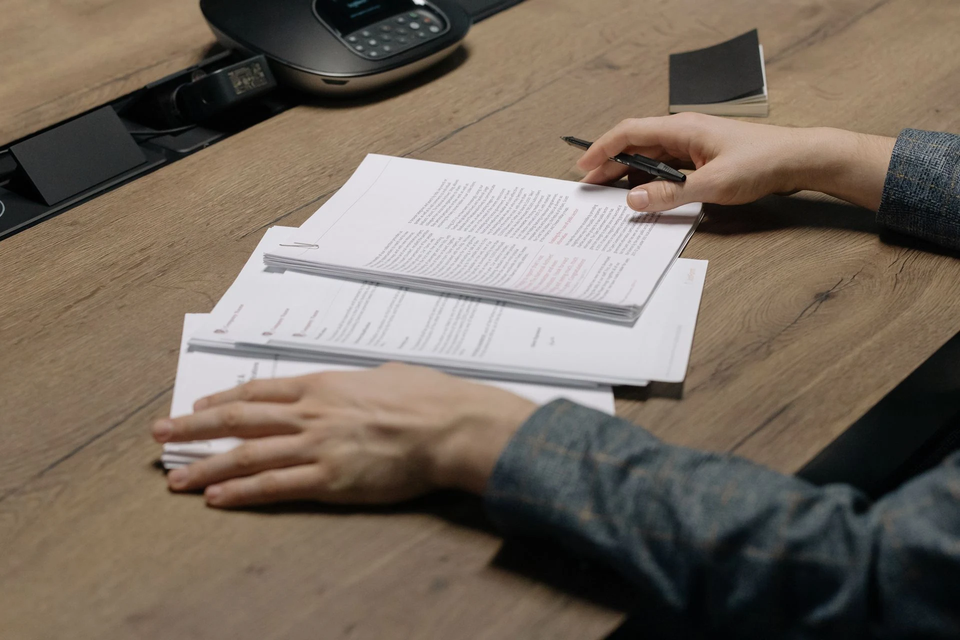 Hand resting on a stack of printed documents on a desk