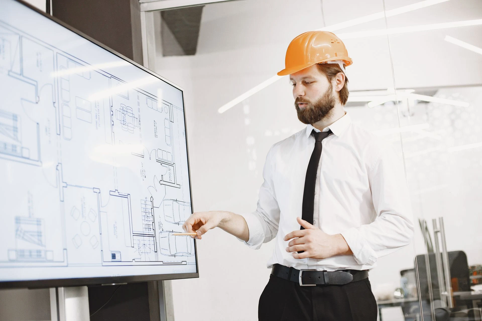 Engineer in a hard hat presenting building plans on a large screen