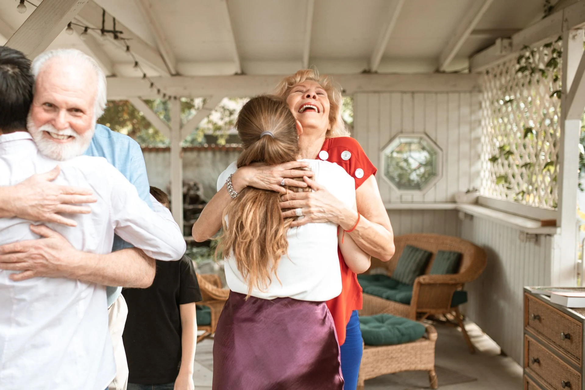 Grandparents embracing visiting family members on a porch