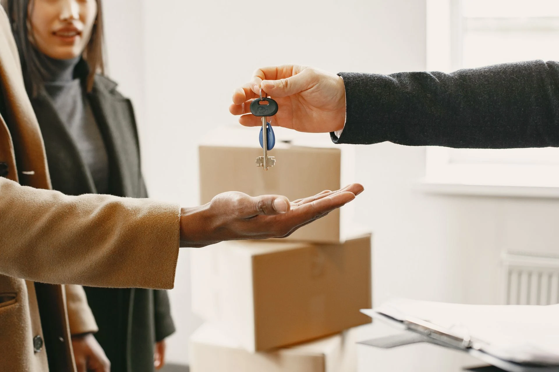 Hand passing a set of keys to another person's open hand