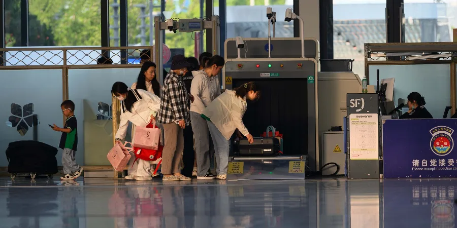 Passengers placing bags on an airport security scanner