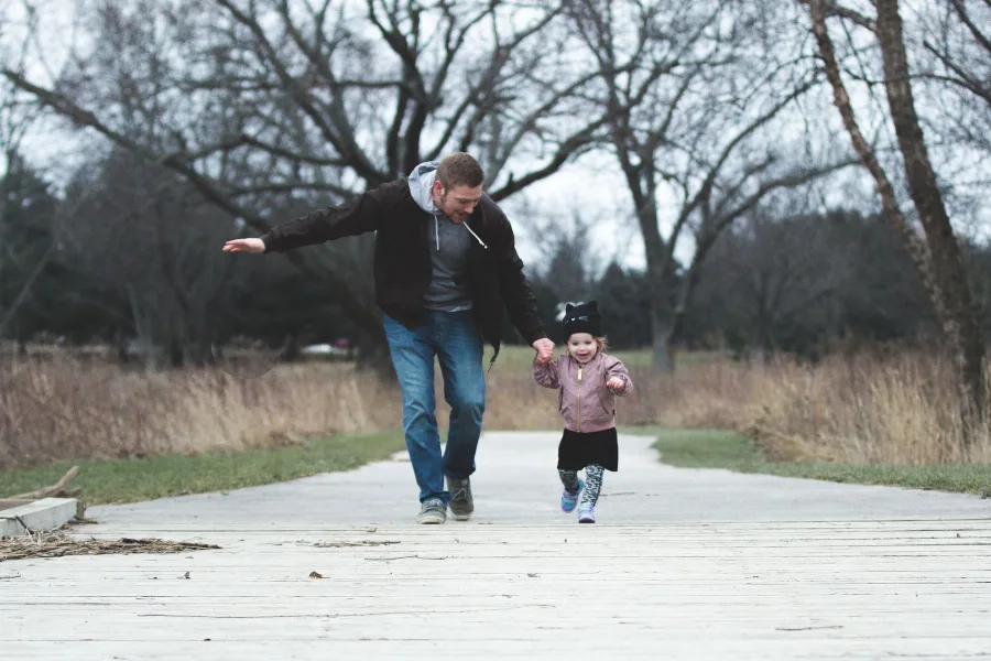 Father running along a path with a small child in winter