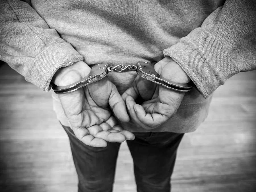 Hands in handcuffs behind a person's back, black and white