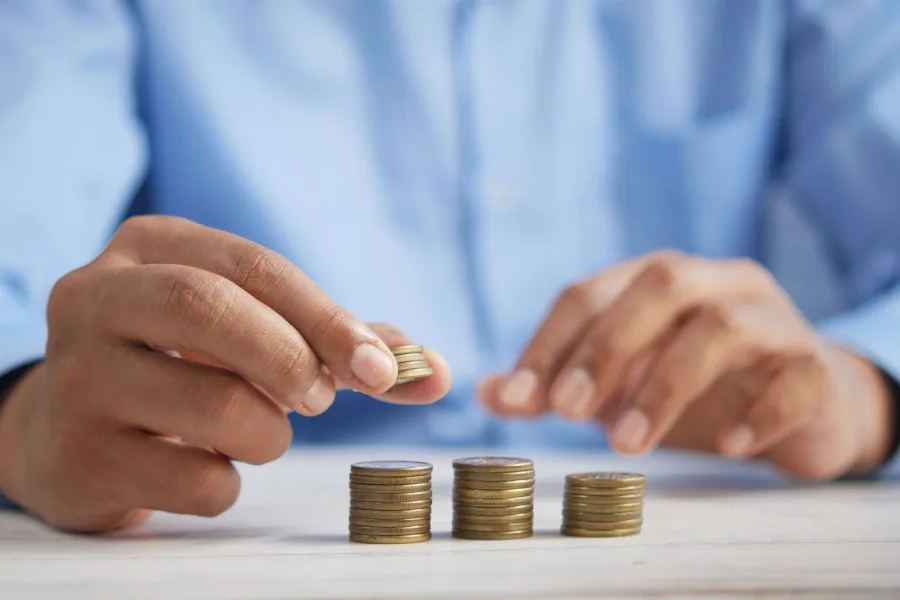 Close-up of hands stacking gold coins