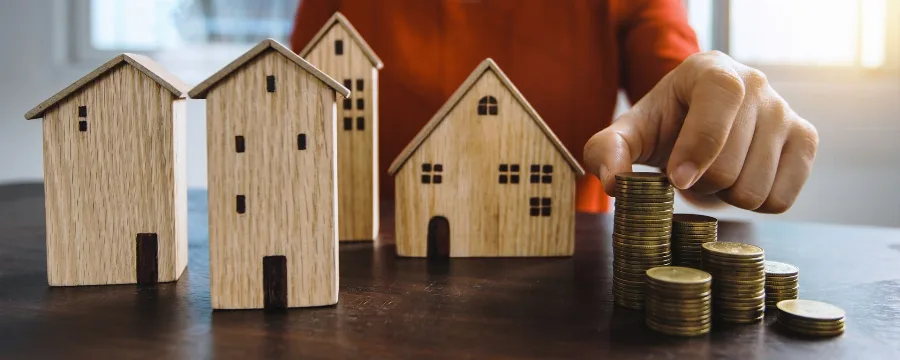 Wooden model houses beside stacks of coins