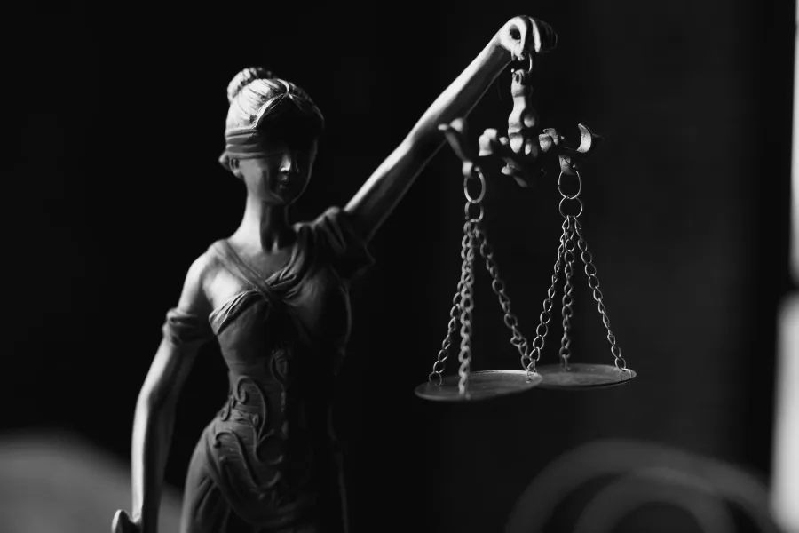 Statue of Lady Justice holding scales against a dark background