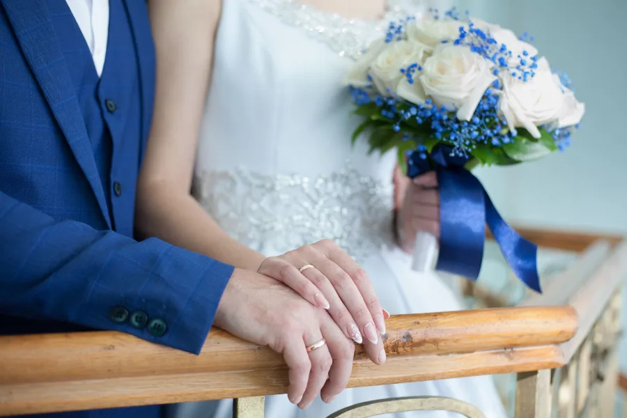 Bride and groom's hands resting together beside a bouquet