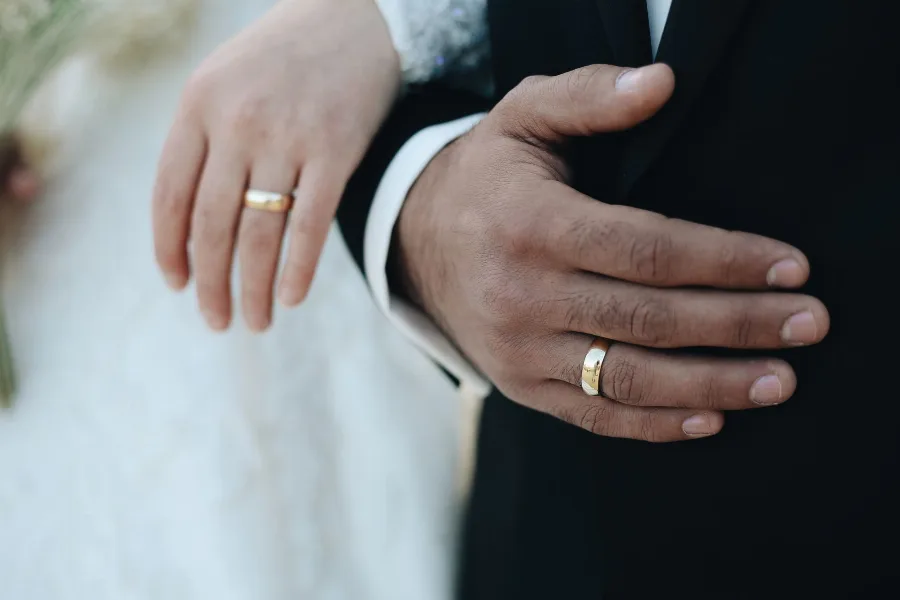 Close-up of a couple's hands wearing wedding rings