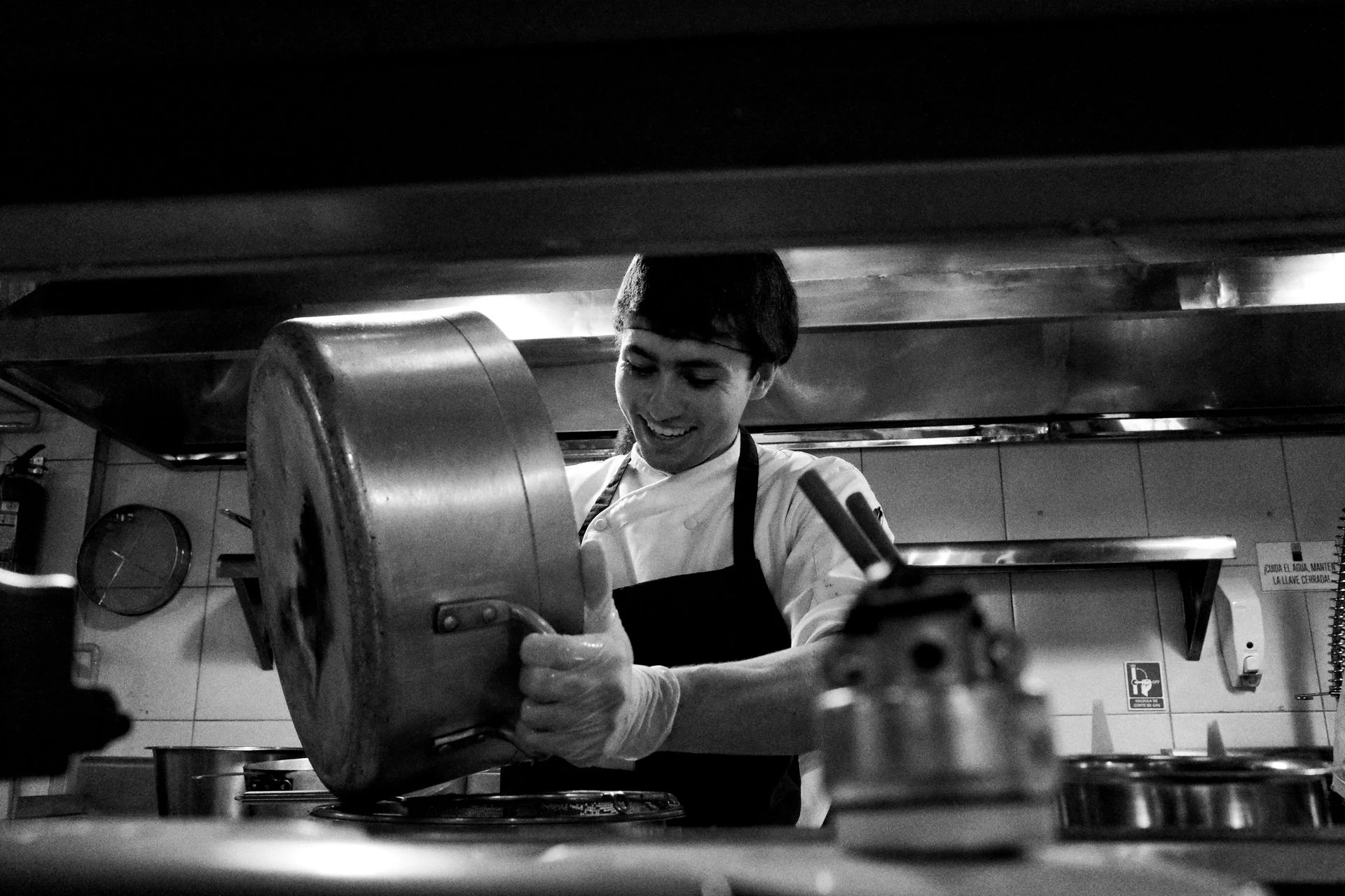 Cook working at a stove in a restaurant kitchen, black and white