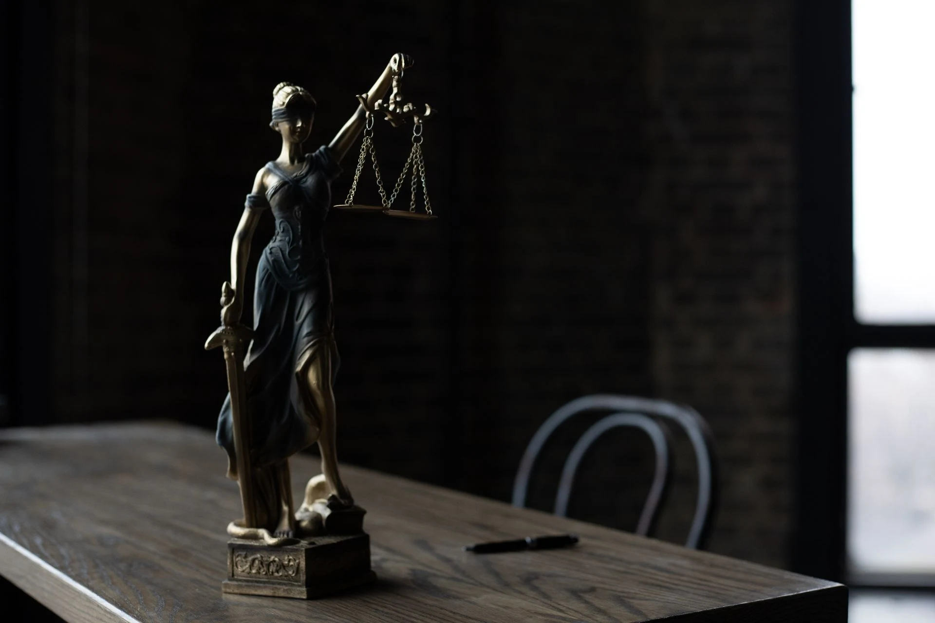 Statue of Lady Justice on a table in a dark room