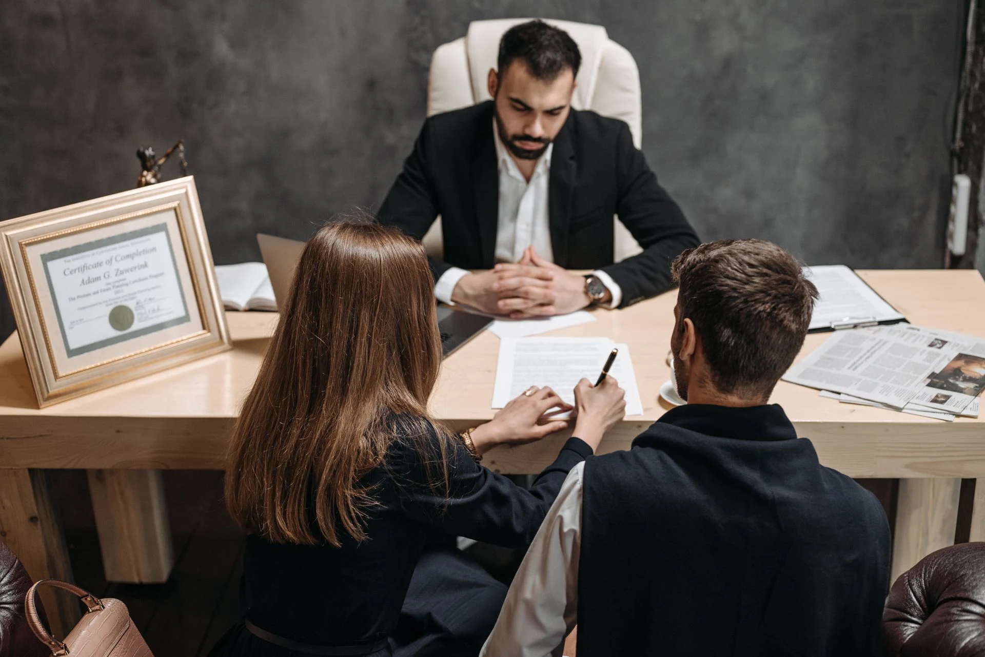 Lawyer at a desk reviewing documents with two clients during a consultation