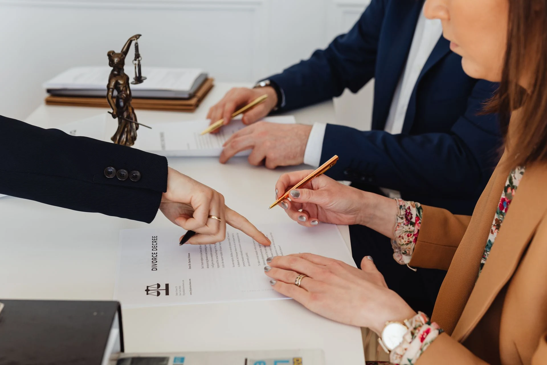 Lawyer pointing to a document while a client signs it at a desk