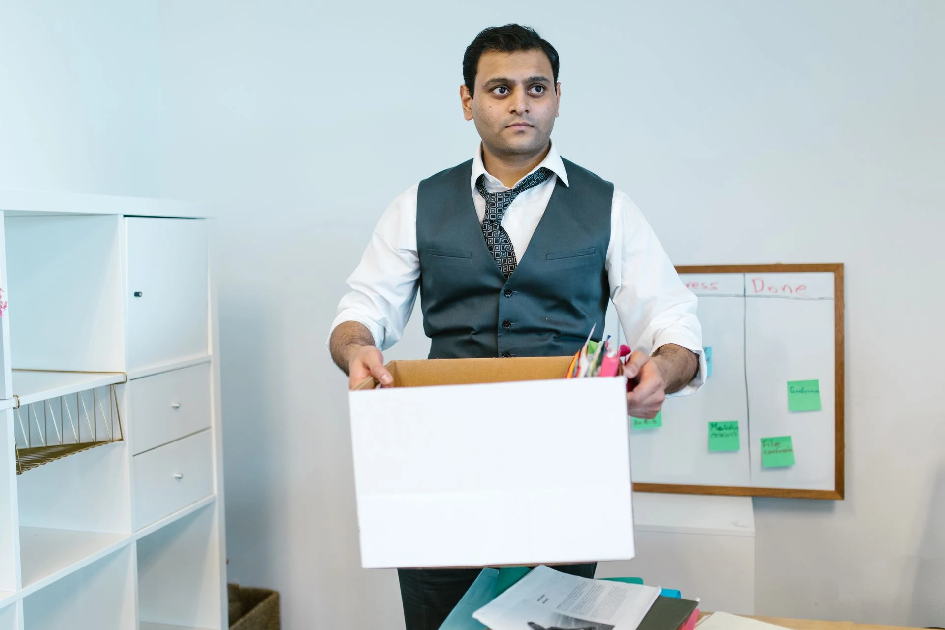 Man in office clothes carrying a cardboard box of belongings