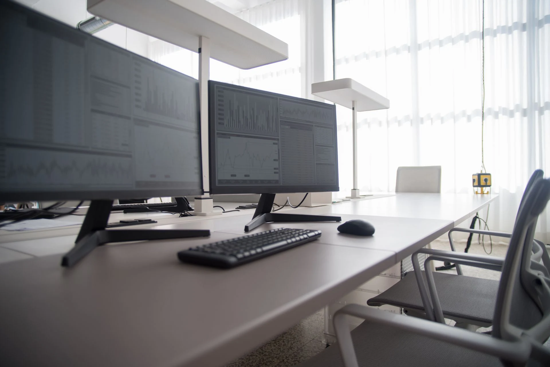 Desk with two computer monitors in a bright office