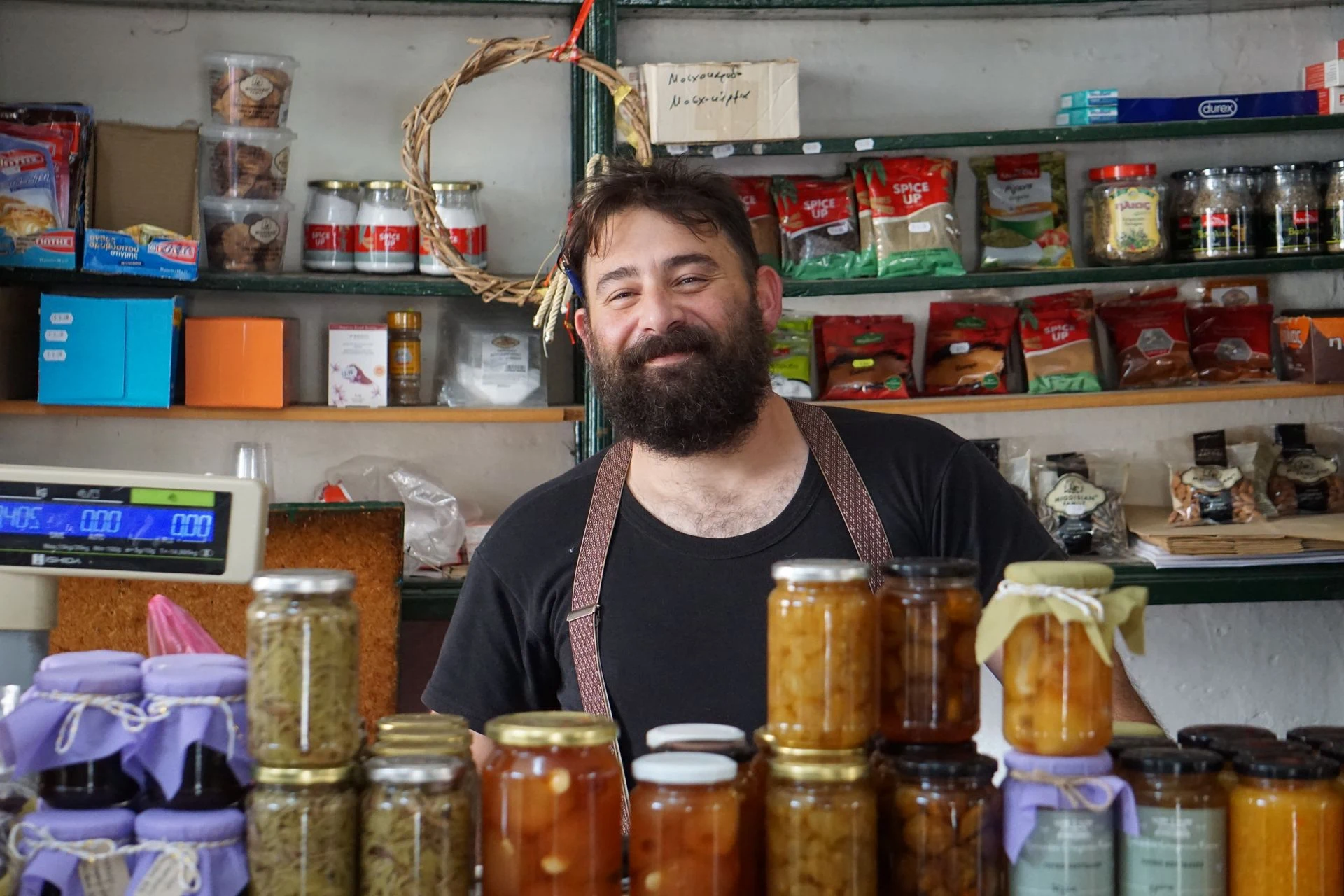 Shop owner standing behind a counter filled with jars and local products