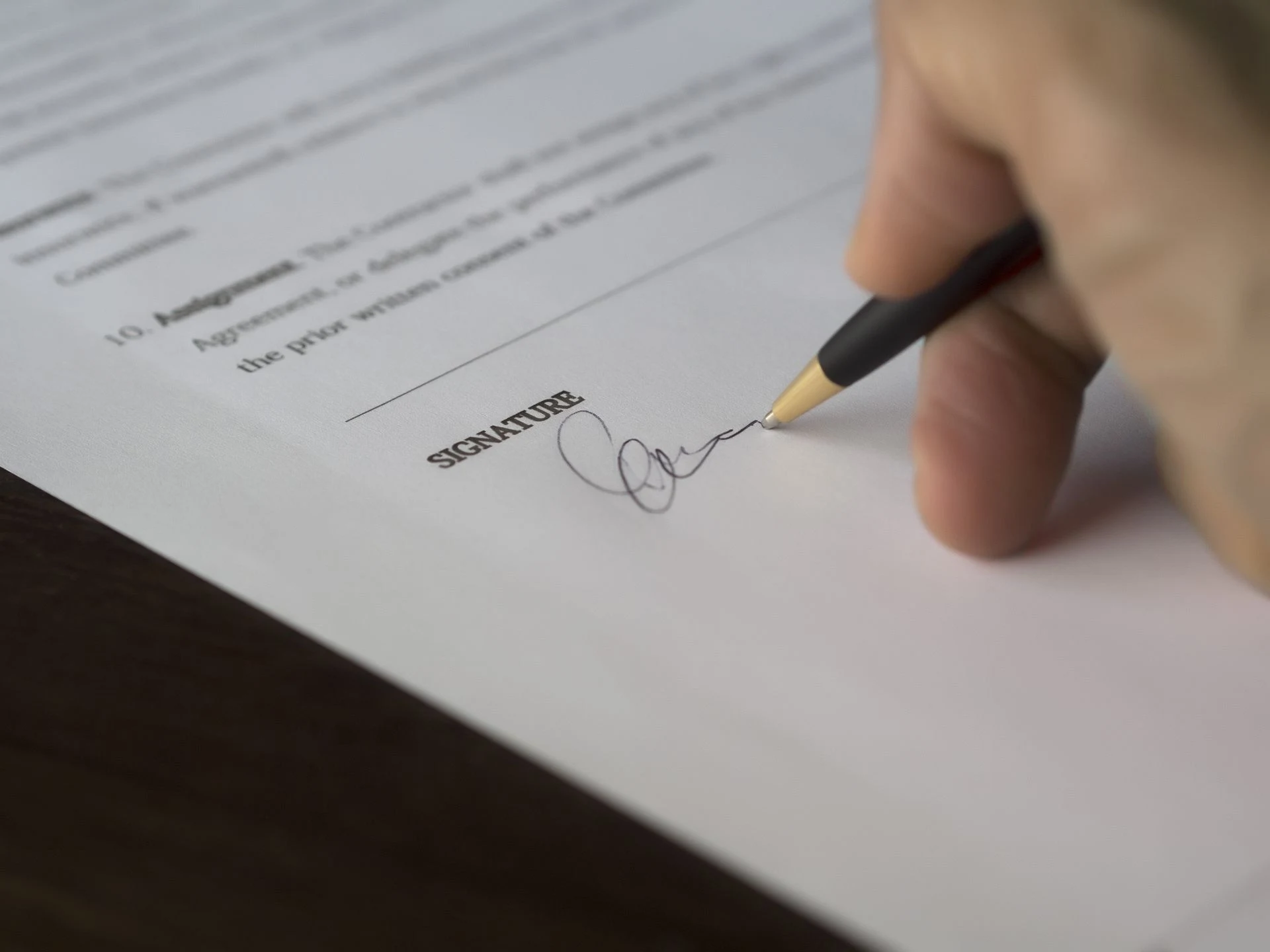 Hand signing a contract with a pen