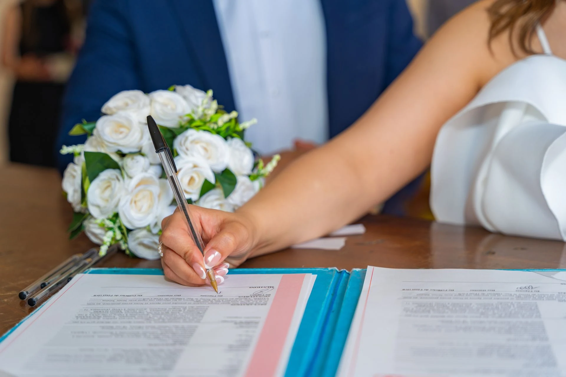 Bride signing the marriage register at a table with flowers